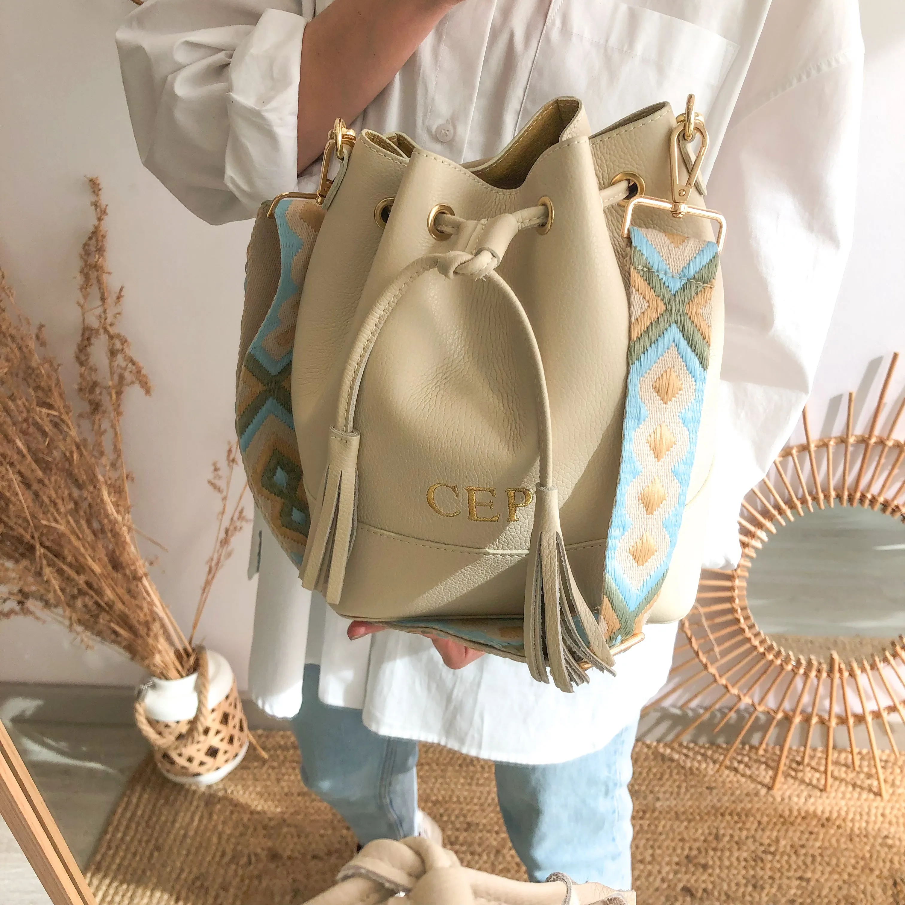 Bolso bucket piel beige pompón iniciales bordadas